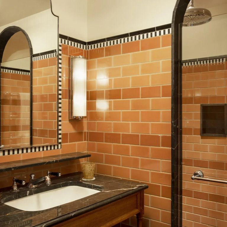 Elegantes Badezimmer mit orangefarbenen Fliesen und Spiegel