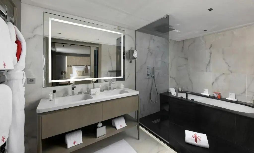 Modernes Badezimmer mit großer Spiegelbeleuchtung und geräumiger Dusche.