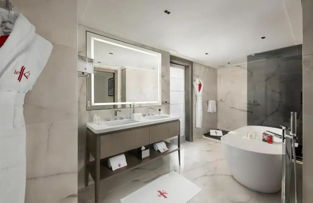Helles Badezimmer mit freistehender Badewanne, großem Spiegel und moderner Ausstattung.