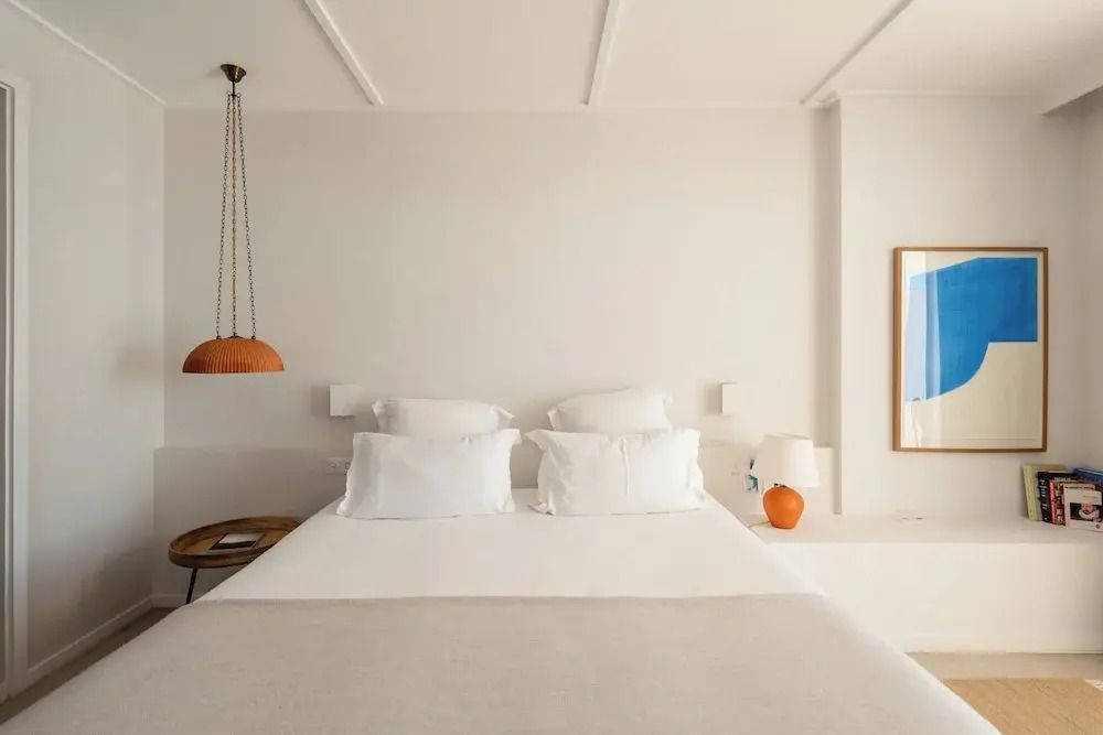 Doppelbett in minimalistischem Zimmer mit weißen und orangen Akzenten