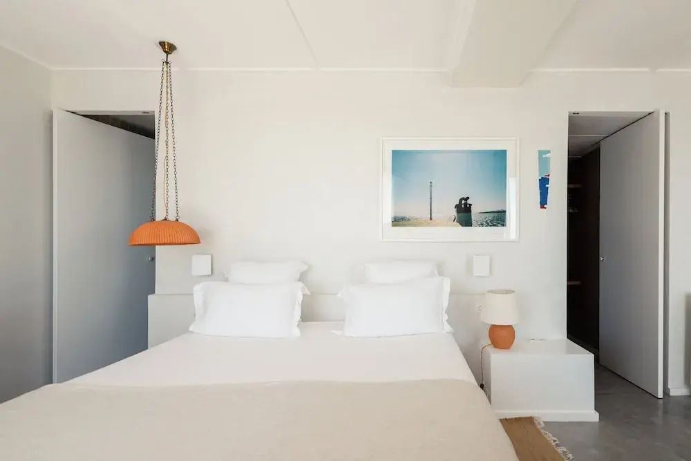 Helles Schlafzimmer in der Junior-Suite mit Kunstwerk an der Wand und stilvoller Beleuchtung