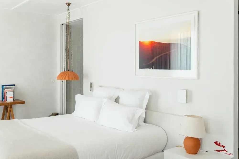 Gemütliches Bett in der Junior-Suite mit einem Sonnenuntergangsgemälde an der Wand