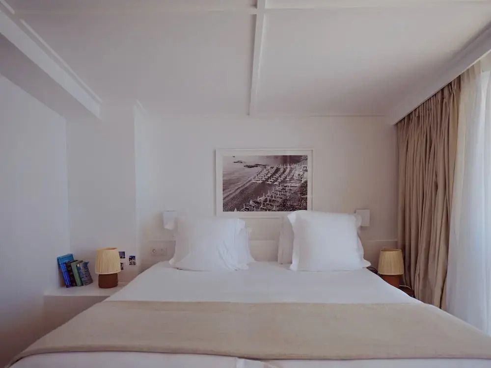 Doppelbett in einem eleganten Zimmer mit minimalistischer Dekoration und Kunstwerk an der Wand