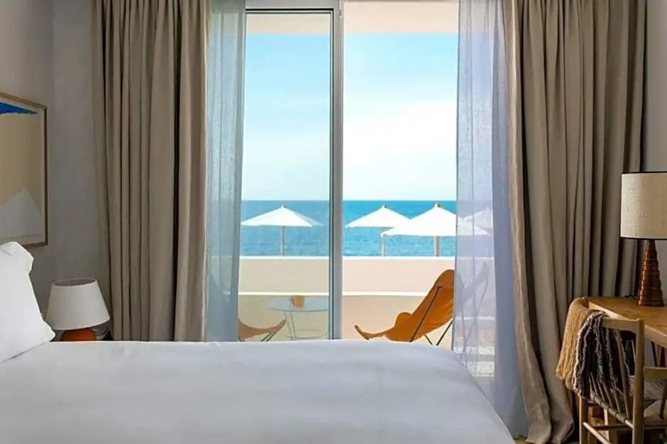 Schlafzimmer mit Blick auf Meer und weißen Sonnenschirmen von Balkon aus