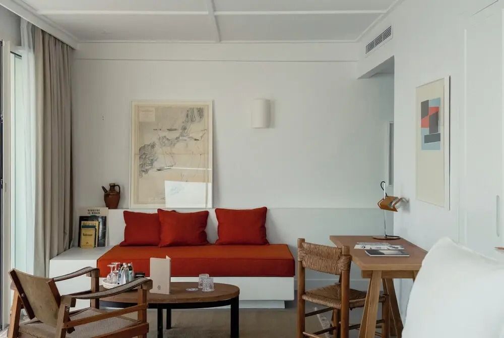Wohnbereich mit roten Kissen und Holzdetails in der Suite mit Meerblick.