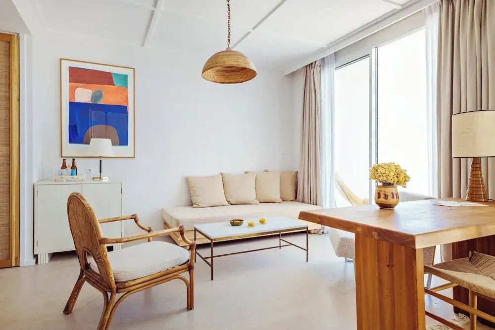 Heller Wohnbereich mit Kunstwerk und Rattanstühlen in der Suite mit Meerblick.