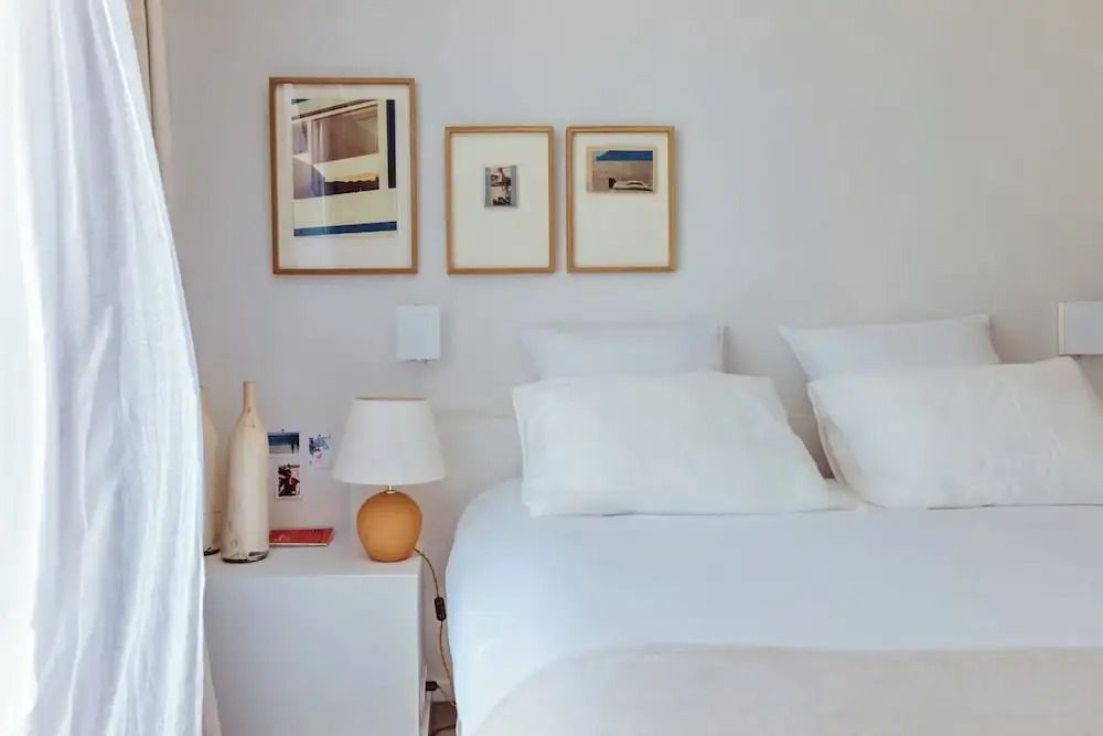 Schlafbereich mit weißem Bett und gerahmten Bildern an der Wand.