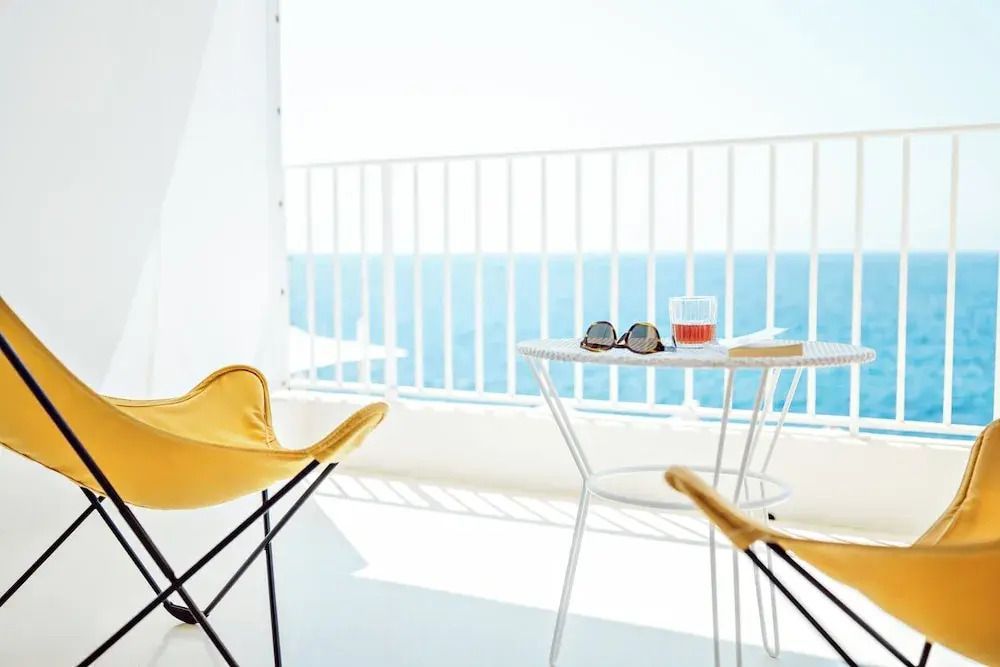 Balkon mit Blick aufs Meer, weiße Möbel und Sonnenbrille auf Tisch