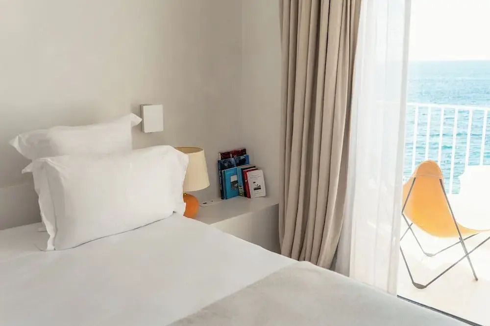 Ecke des Zimmers mit Bett, Nachttisch und Vorhang