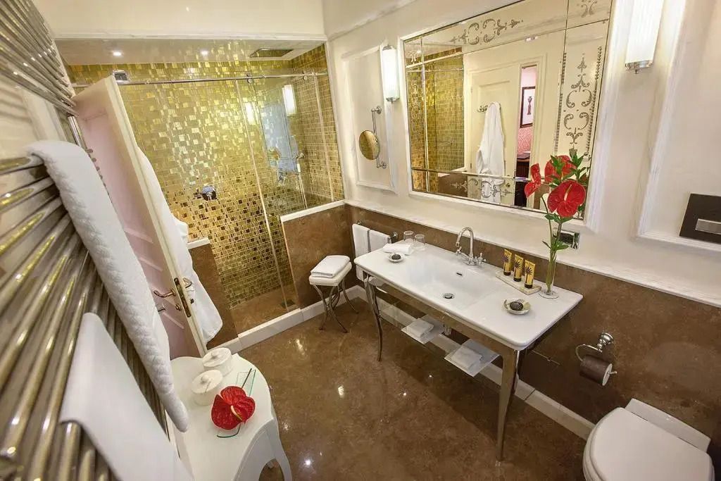 Elegantes Badezimmer mit goldenen Akzenten und großer Spiegelwand