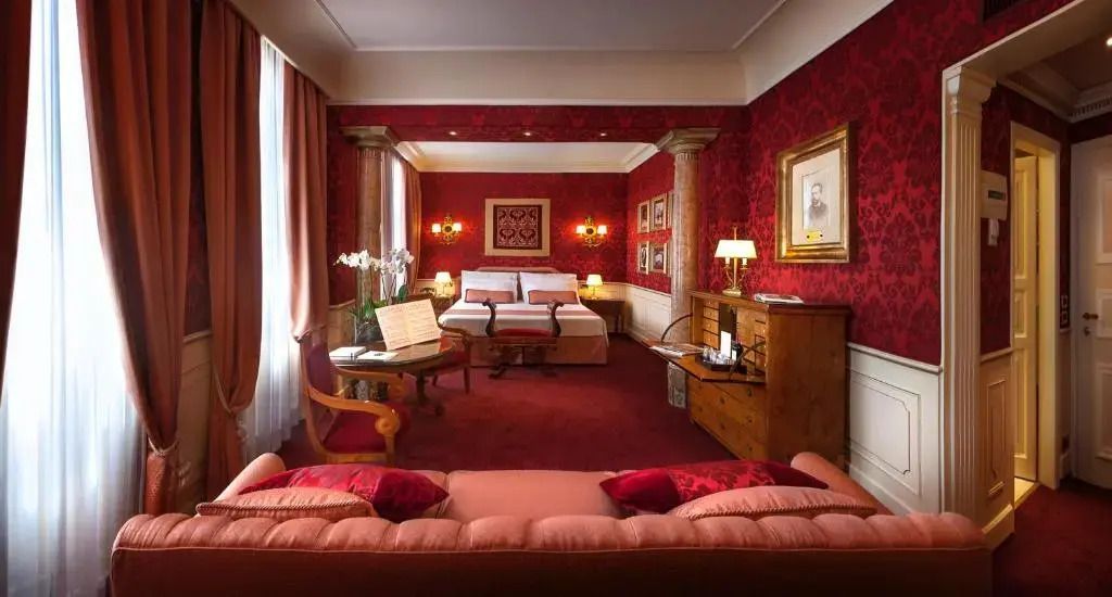 Geräumiges Zimmer mit luxuriöser Einrichtung in warmen Rottönen und klassischem Stil