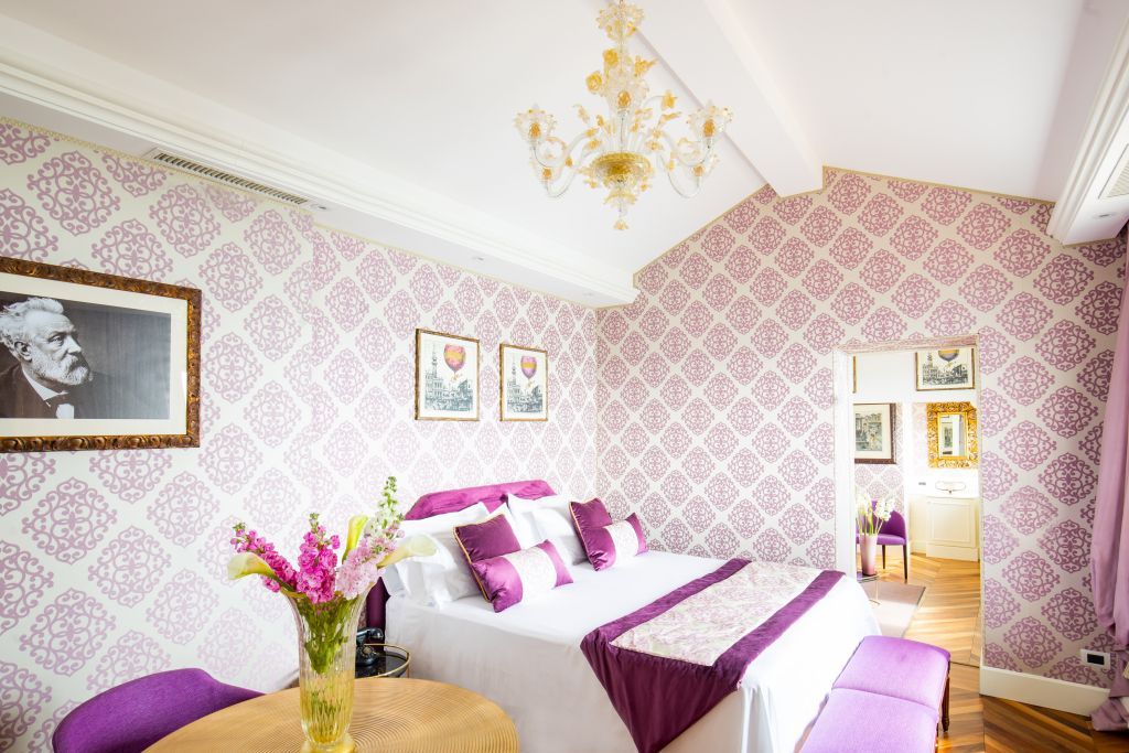 Doppel Suite mit lila Dekoration und gemütlichem Doppelbett mit Blumenarrangement