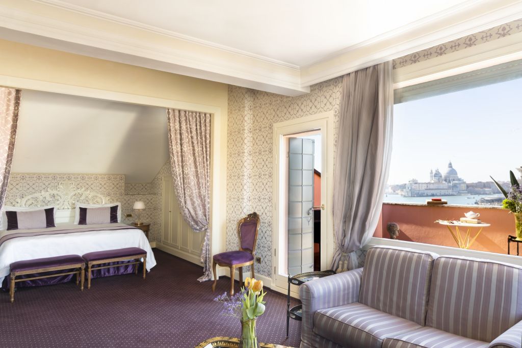 Elegante Suite mit Doppelbett, stilvollem Sofa und Zugang zur Terrasse mit Aussicht