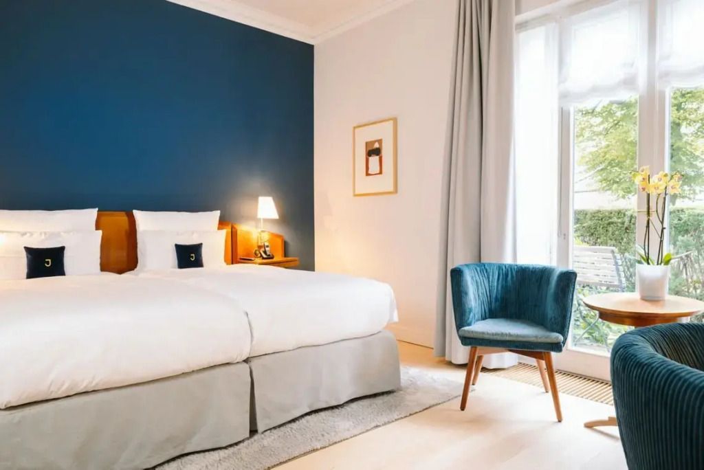 Modernes Deluxe Doppelzimmer mit blauem Akzent und elegantem Sessel