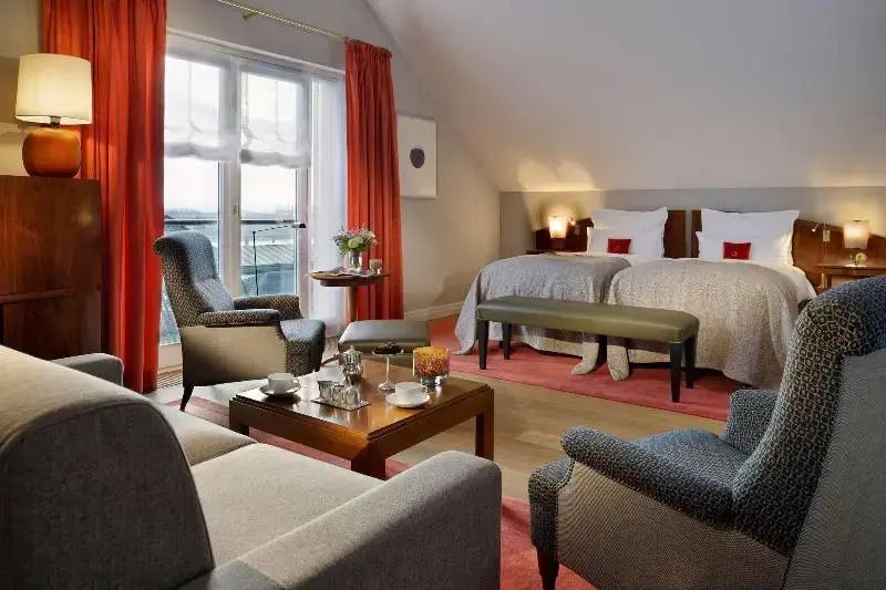 Komfortable Suite mit Doppelbett und Sitzbereich vor großen Fenstern