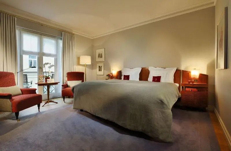 Großes Doppelbett in einem elegant eingerichteten Zimmer mit Sitzmöglichkeiten