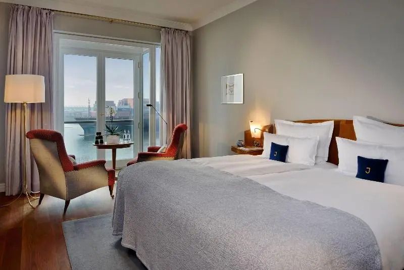 Großes Doppelbett in stilvollem Zimmer mit Flussblick.
