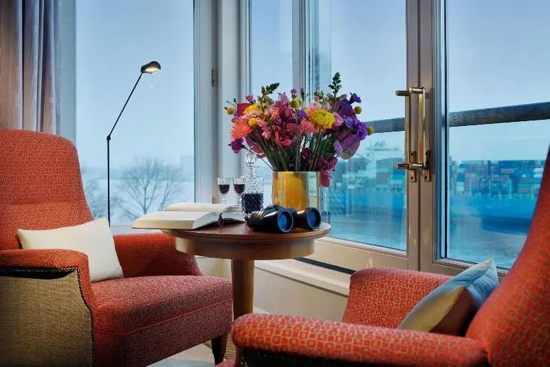 Blumenarrangement auf Tisch in gemütlicher Ecke mit Fensterblick.