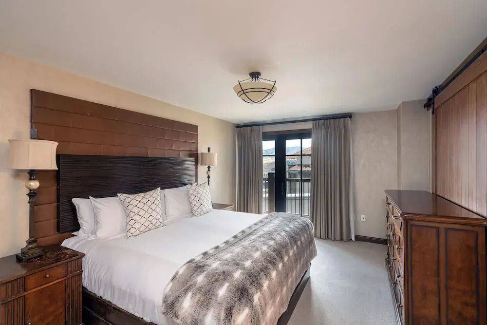 Schlafzimmer mit großem Bett, Holzkopfteil und Balkon mit Bergblick