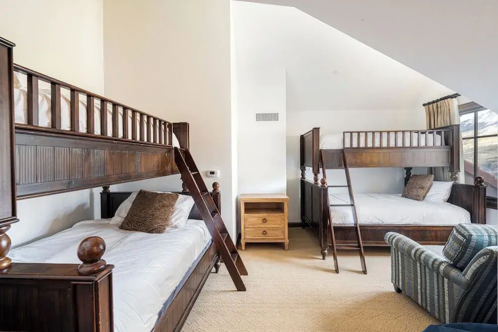 Schlafzimmer mit Etagenbetten aus Holz und neutralem Dekor.