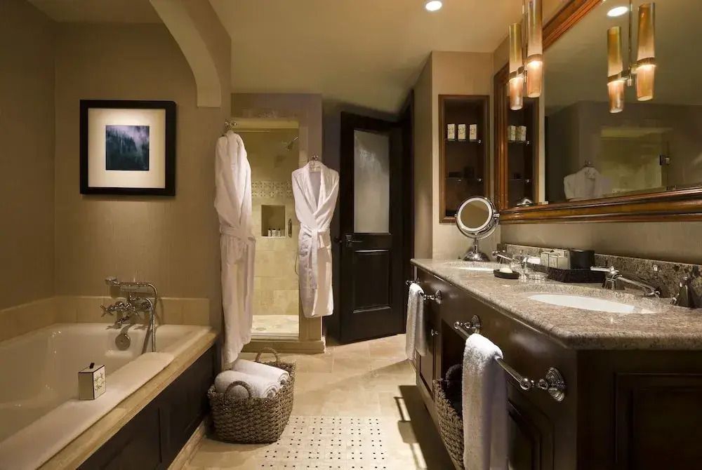 Luxuriöses Badezimmer mit Badewanne Doppelwaschbecken und zwei Bademänteln.