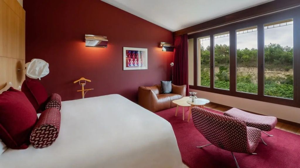 Ruhige Sitzecke mit Sofa und Aussicht auf grüne Umgebung im stilvollen Hotelzimmer.