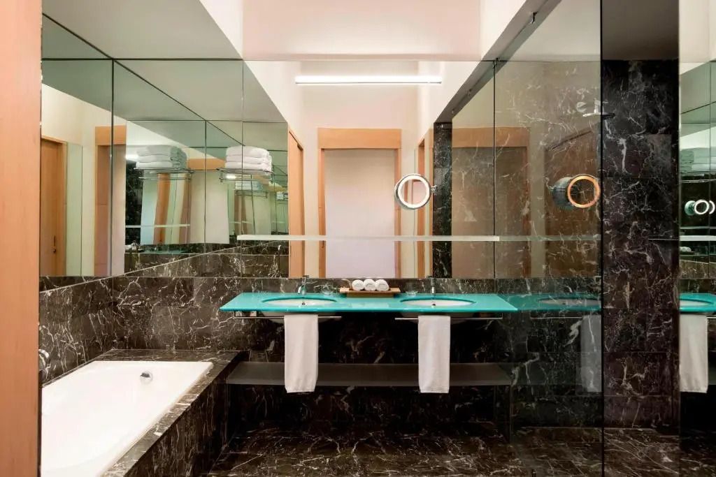 Luxuriöses Badezimmer mit Marmorakzenten, zwei Waschbecken und Badewanne.
