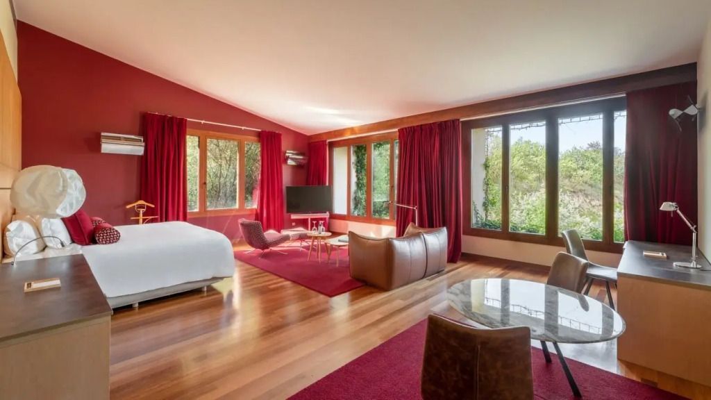 Großzügige Suite mit roten Akzenten und Panoramafenstern mit Gartenblick