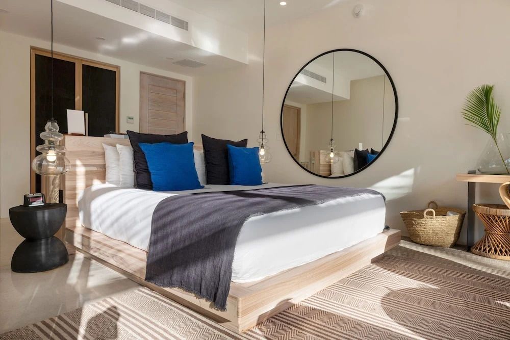 Modernes Schlafzimmer mit großem runden Spiegel und blauer Dekoration.