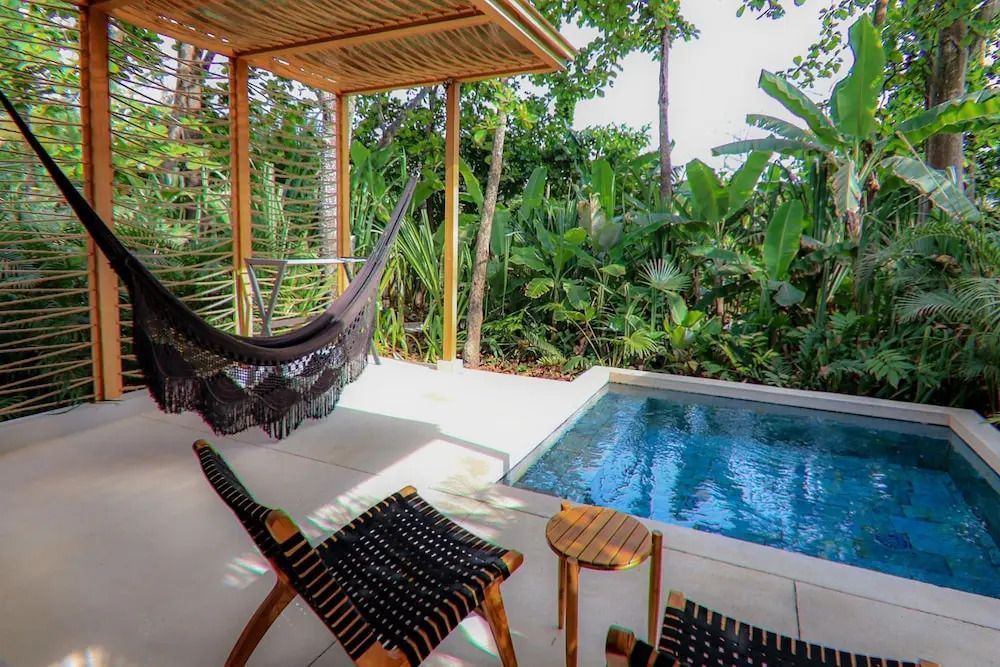 Private Terrasse mit Hängematte und kleinem Pool vor üppiger Vegetation.