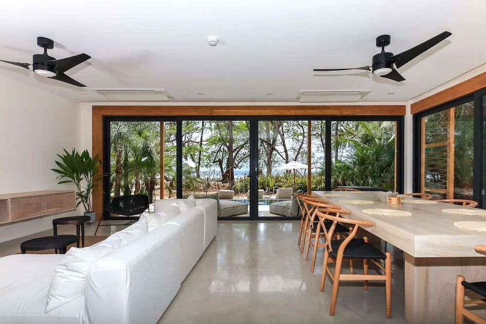 Modernes Wohnzimmer mit weißen Sofas und großem Fenster mit Blick auf den Garten.