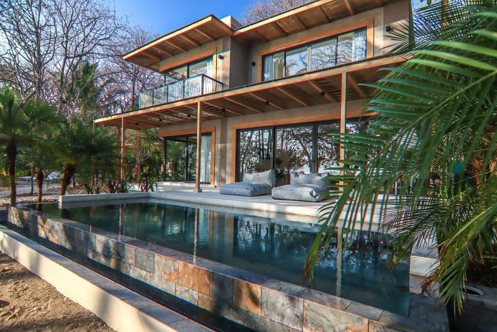 Strandvilla mit Pool und Holzbalken unter klarem Himmel.