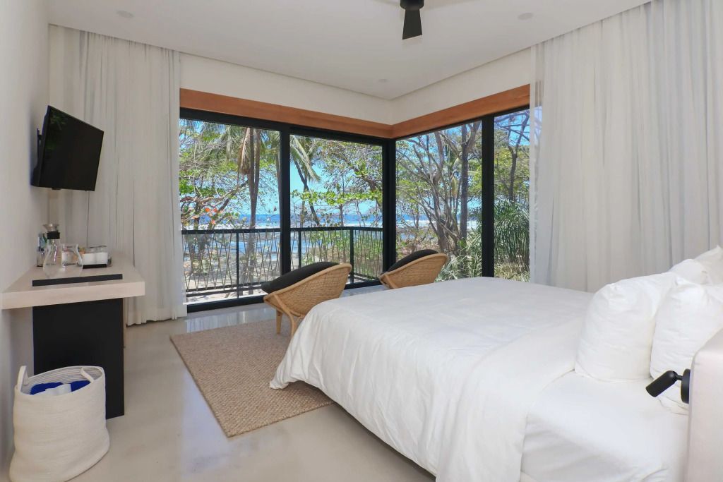 Helles Schlafzimmer mit Blick auf den Strand und bequemen Sesseln.