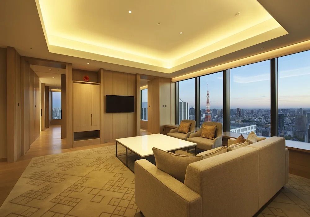 Elegantes Wohnzimmer der Club Doppel Suite mit gemütlichen Sofas und weitreichendem Blick über Tokio.