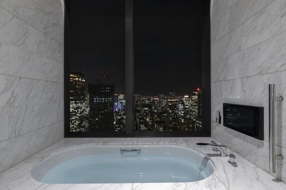 Luxuriöses Badezimmer mit Blick auf die nächtliche Skyline von Tokio.