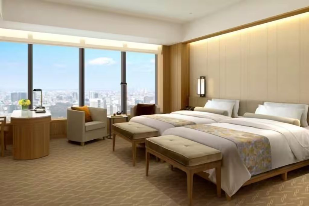 Helles Hotelzimmer mit zwei Einzelbetten und großer Fensterfront mit Stadtblick