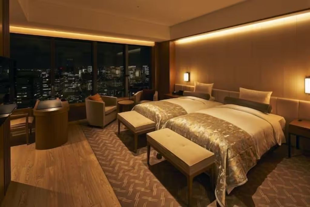 Gemütliches Hotelzimmer bei Nacht mit zwei Einzelbetten und beleuchtetem Stadtblick