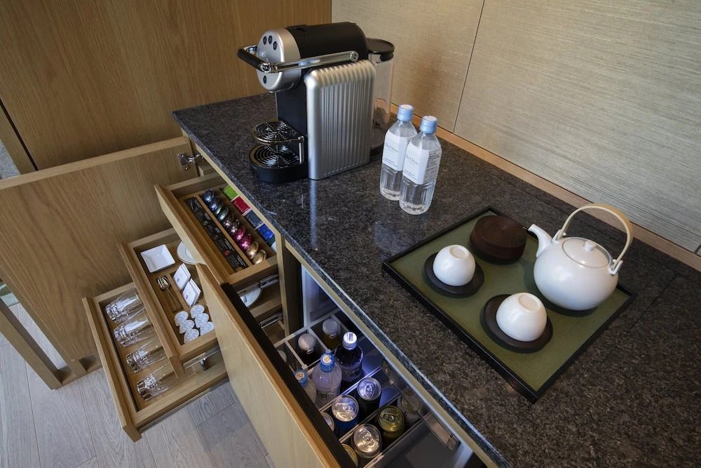 Getränkestation mit Tee- und Kaffeezubehör und Wasserflaschen in der Suite.