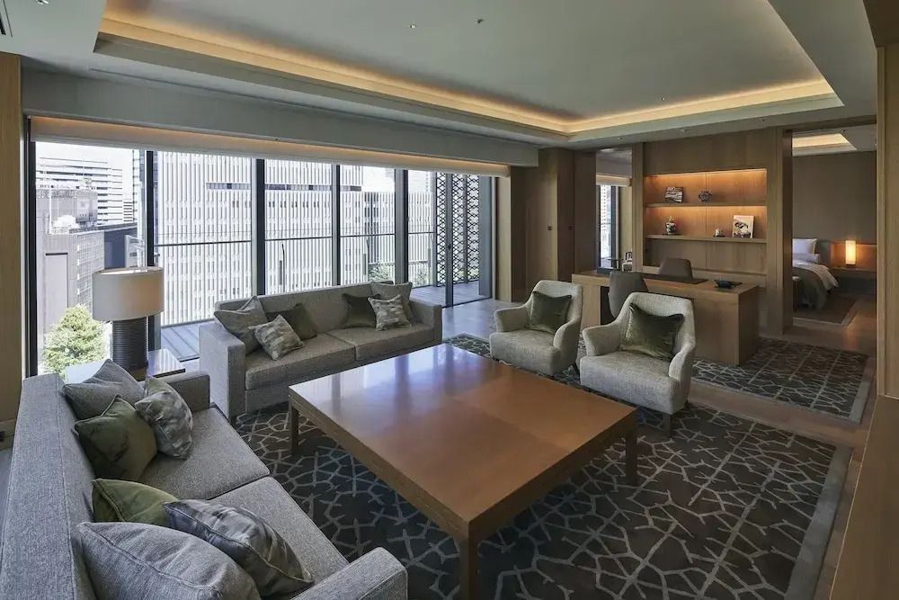 Helles Wohnzimmer mit Sofas und Zugang zum Balkon in einer luxuriösen Suite.