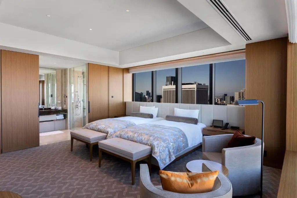 Großzügiges Zimmer mit zwei Einzelbetten und Panoramafenstern mit Stadtansicht.