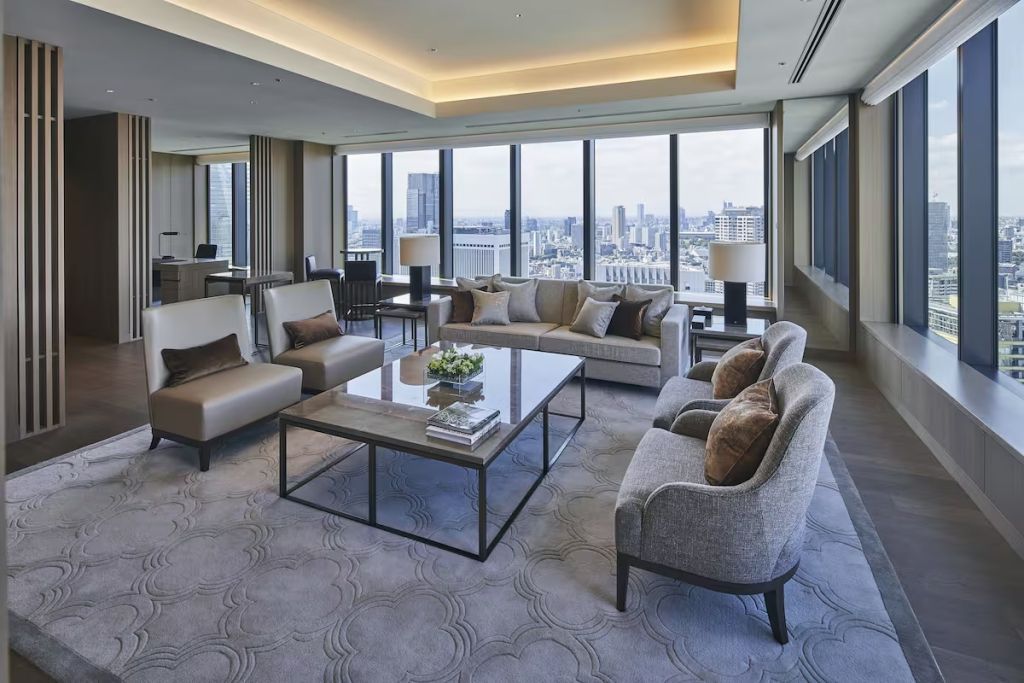 Geräumiges Wohnzimmer der Suite mit großen Fenstern und eleganter Sofagarnitur.
