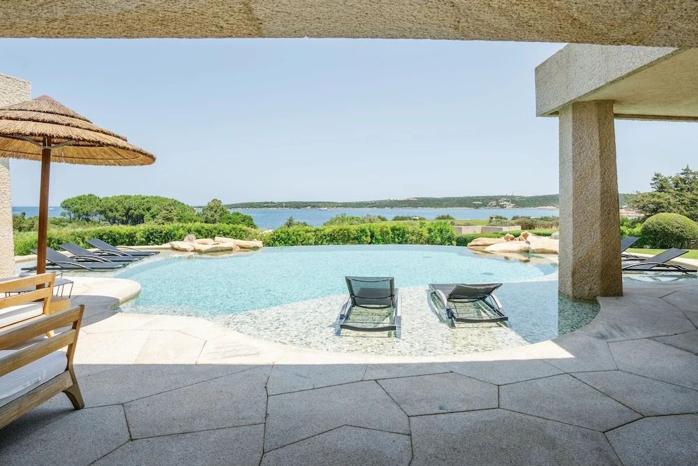 Infinity-Pool mit Blick auf die Küste und Liegestühle unter einer Überdachung