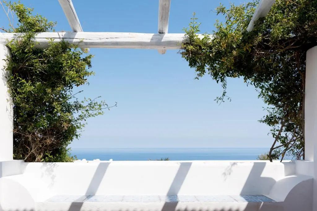 Weißer Pergola-Blick auf das Meer mit grüner Bepflanzung
