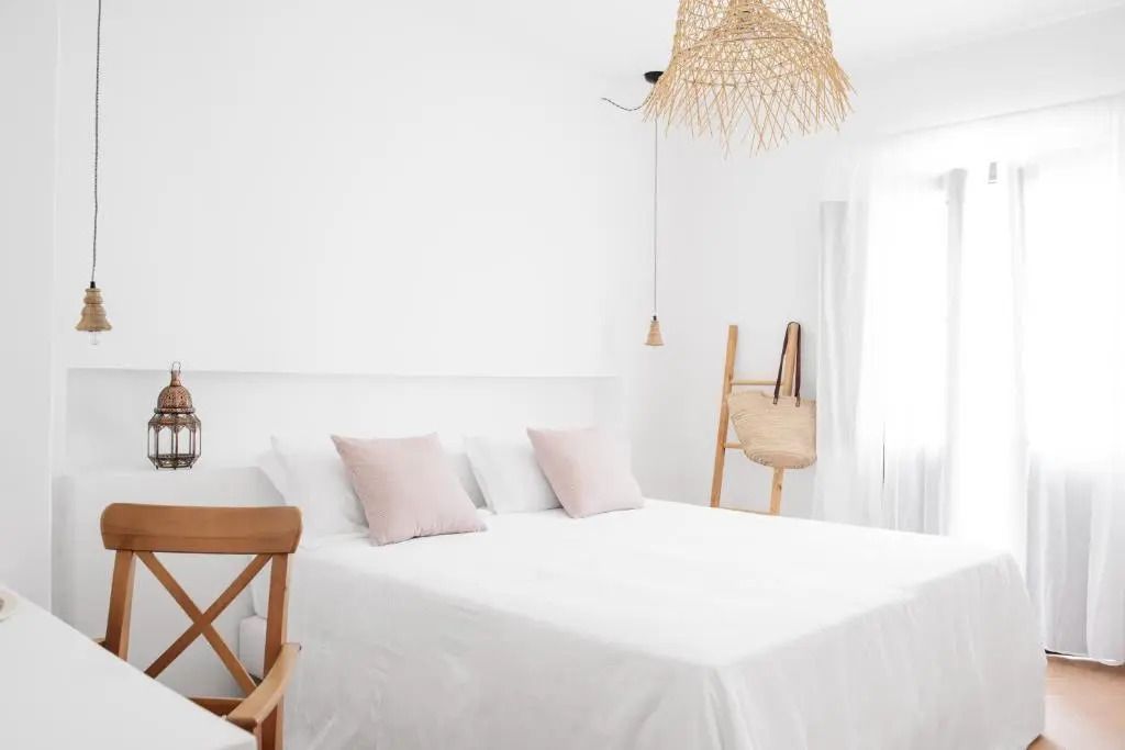 Lichtdurchflutetes Doppelzimmer mit Naturdeko und weißen Vorhängen