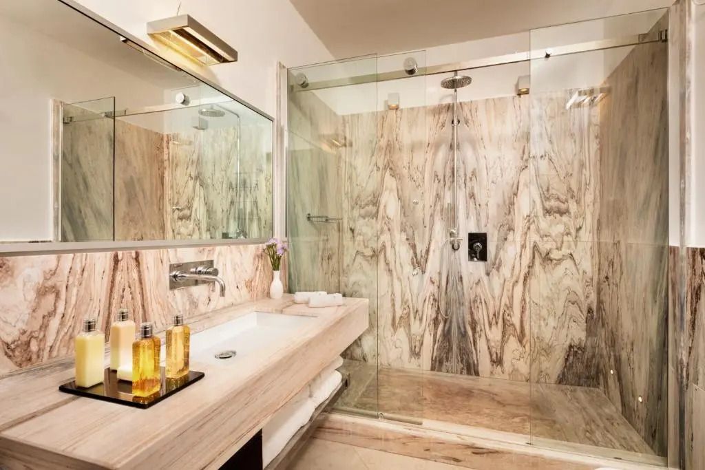 Modernes Badezimmer mit begehbarer Dusche und Marmorakzenten im Punta Tragara Hotel