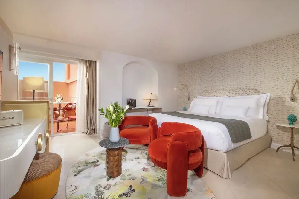 Charmantes Hotelzimmer mit Doppelbett, gemusterten Stühlen und Balkon in Punta Tragara