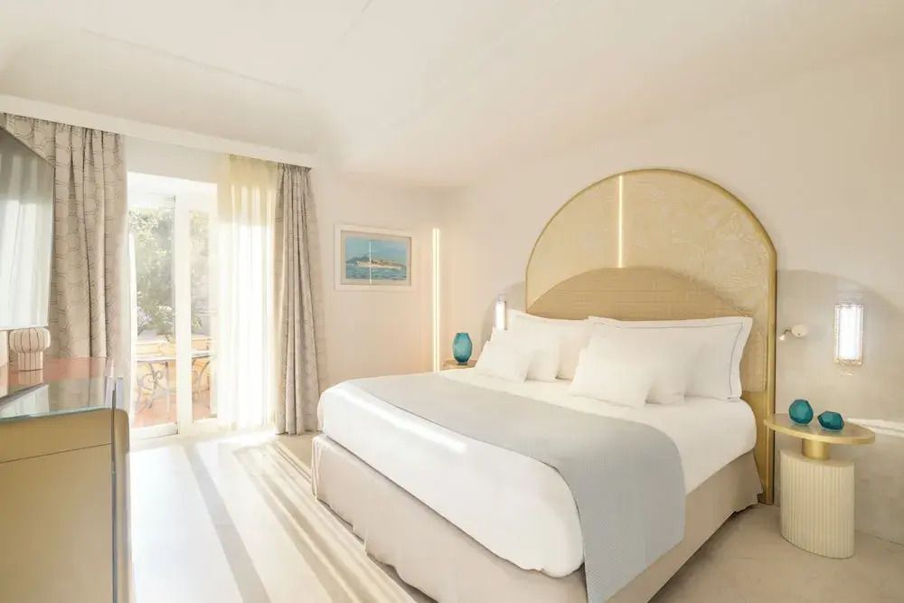 Helles Hotelzimmer mit Doppelbett, großem Fenster und moderner Dekoration in Punta Tragara