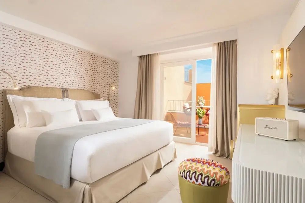 Hotelzimmer mit Doppelbett und Zugang zu einem sonnigen Balkon
