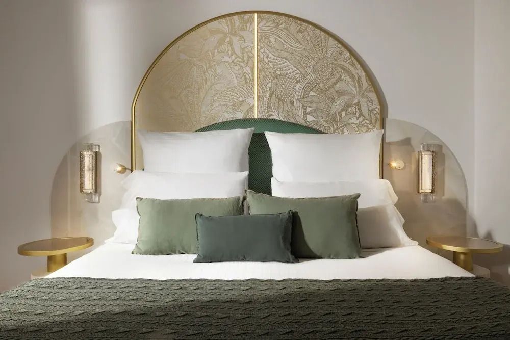 Luxuriöses Bett im Prestige Zimmer mit dekorativem Kopfteil und grünen Kissen