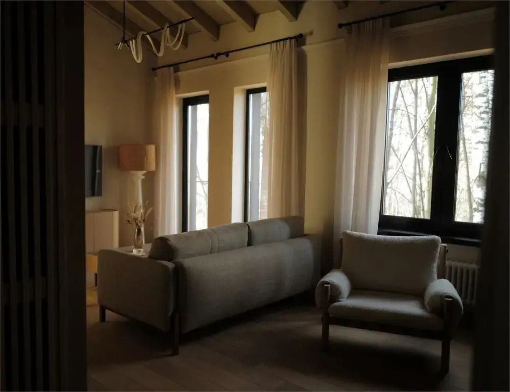 Gemütliches Wohnzimmer mit Sofa und Sessel in der Suite mit zwei Fenstern